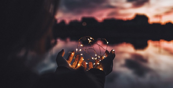 A person holding lights outside before sunset