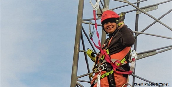 A smiling worker on a telecommunication tower