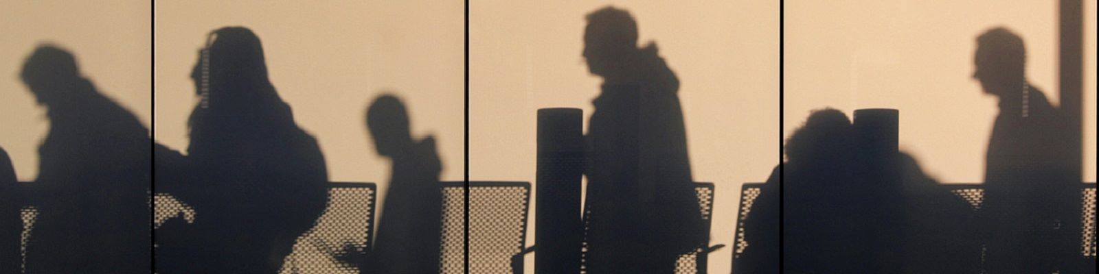 Silhouettes of people moving through an airport