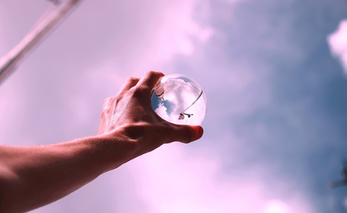 Hand holding a glass orb to the sky